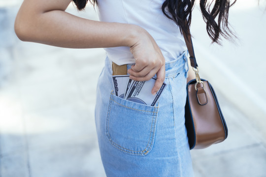 女人捡起钞票时裤子口袋里钞票的剪短图像。