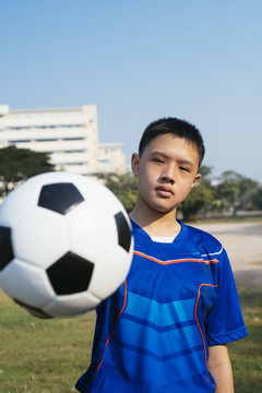 一个小足球运动员把球放在他面前。