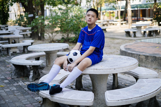 足球机器人坐在大理石长凳上拿着他的足球。