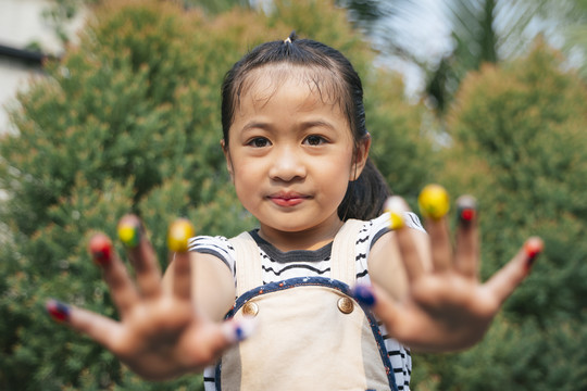 特写亚洲小女孩，手指头上涂有彩色颜料。