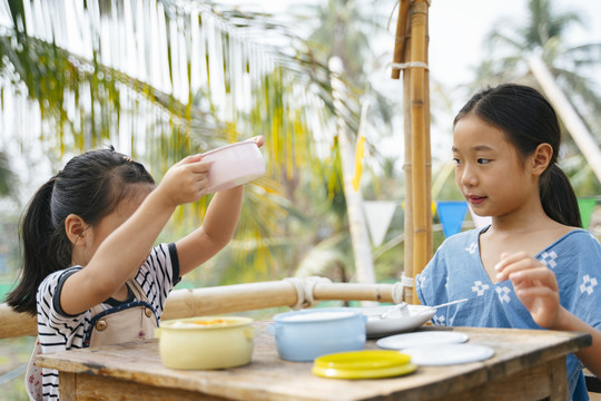 小妹妹一边要米饭，一边举起粉红色的平托食品容器。泰国传统午餐文化。