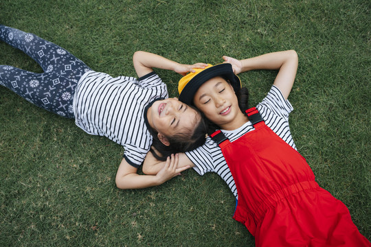 两个亚洲妹妹幸福地躺在草地上。睡在草地上。