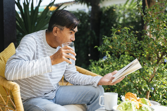 一位白发老人早餐后看书时很兴奋。