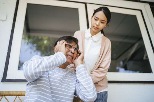 白发老人在私人护士家访时头痛，低角度拍摄。