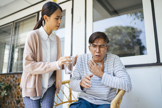 白发老人呛咳，私人护士给他一杯水。