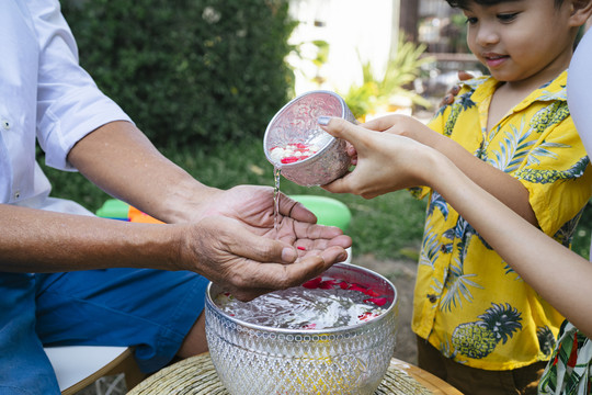 在传统节日里，女儿和儿子将花水倒在父亲的手上时，银杯和手的剪影。