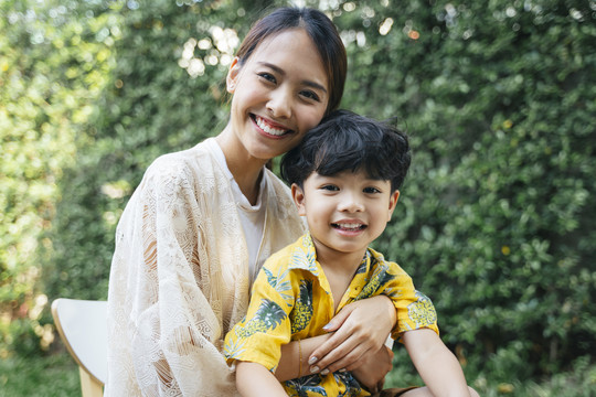 小男孩坐在妈妈的腿上，妈妈用爱拥抱着他。