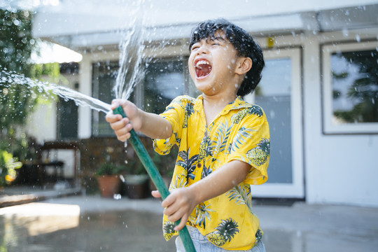 泰国一年一度的传统节日“泼水节”，一个小男孩在他家里用水枪和橡皮管泼水。