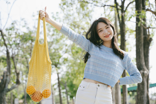 穿着蓝色t恤的可爱女孩微笑着把网袋拉起。