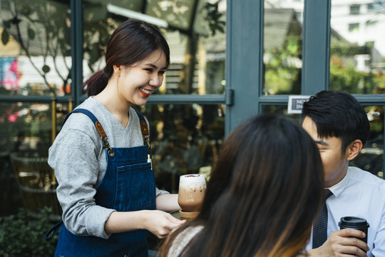 咖啡店的女服务员正在给顾客端盘子里的冰咖啡。