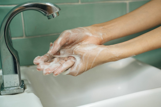 卫生观念。用肥皂洗手的水龙头下有水的绿色卫生间卫生间。在流水下用肥皂洗手。
