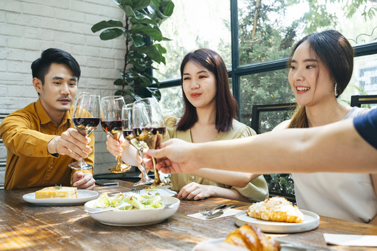 三个亚洲人举杯敬酒。庆祝派对。人们用酒欢呼庆祝。在餐馆吃饭。