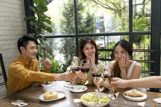 三个亚洲人举杯敬酒。庆祝派对。人们用酒欢呼庆祝。在餐馆吃饭。