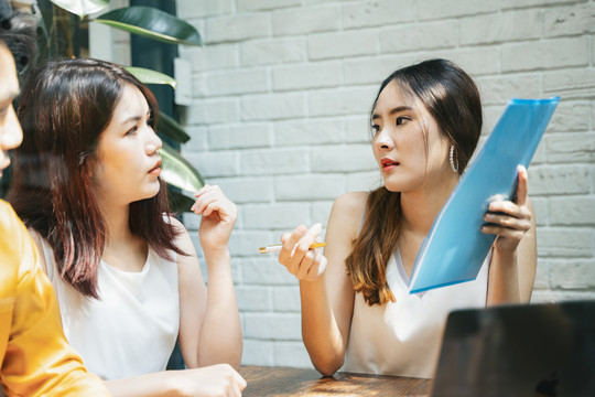 两位亚洲女商人神情严肃地在会议室讨论商业计划。