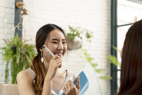 可爱的亚洲女服务员在餐厅里向顾客点菜。