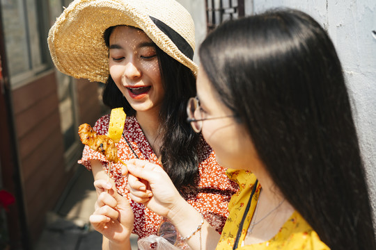 两位年轻漂亮的泰国亚裔旅行家女闺蜜一起在泰国享受街头美食。