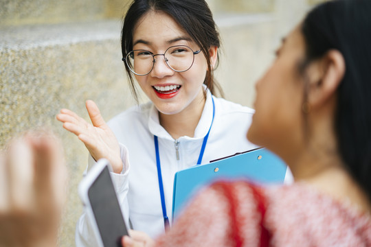 开朗的亚洲导游女士与旅行者女士交谈，为去哪儿指路。