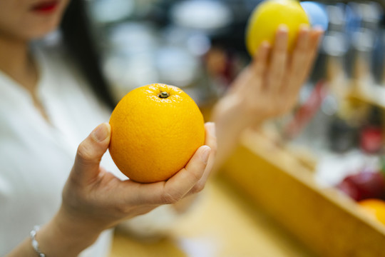 美丽的亚洲女人在超市挑选橘子和柠檬。健康食品选择。维生素C水果。