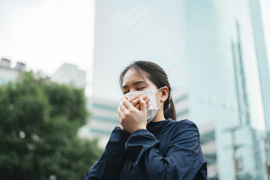 戴着口罩的亚洲妇女在城市里行走时不能呼吸。