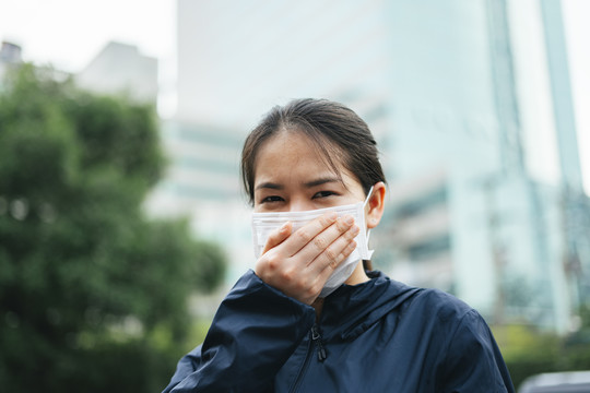 戴着口罩的亚洲妇女在城市里行走时不能呼吸。