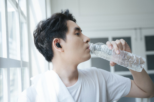 男人停止锻炼，一边喝水一边擦汗。