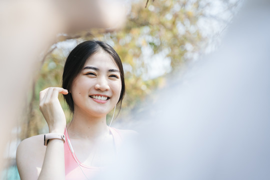 穿着旧玫瑰色运动胸罩的长发女人向跑过来的朋友问好，然后擦汗。