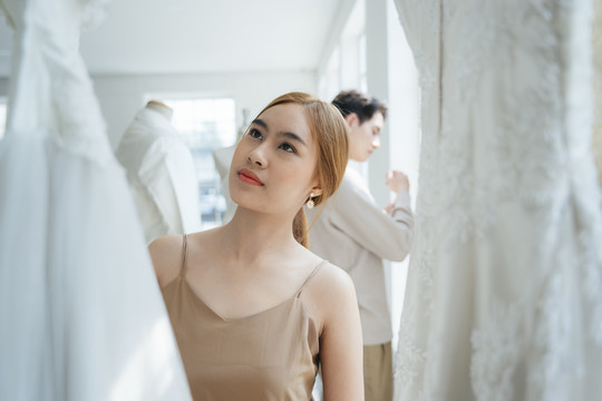 新人参观婚纱摄影棚挑选自己的婚纱，一位女士看婚纱。