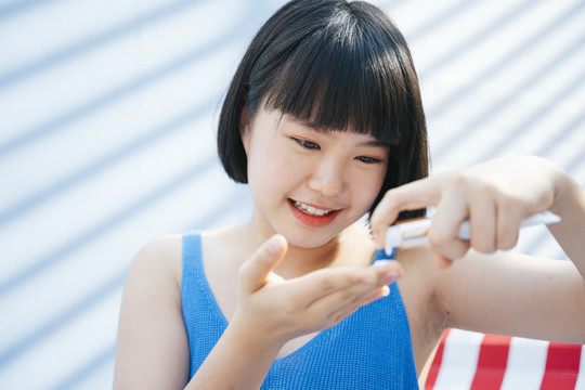 特写美丽的鲍勃理发亚洲女人在蓝色背心衬衫喷射奶油乳液从瓶子。