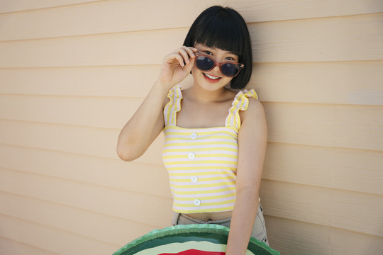 鲍勃理发美丽的亚洲年轻女子穿着黄色背心和太阳镜与救生圈或游泳筒合影。