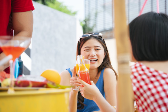 快乐的亚洲女人在夏日聚会上和人们一起举杯。