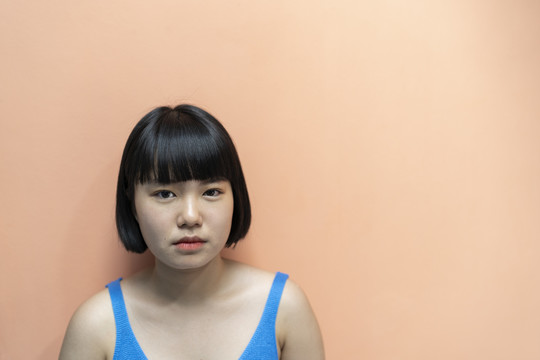 年轻的泰国bob发型女人的肖像，在米色背景下有着不愉快的表情。