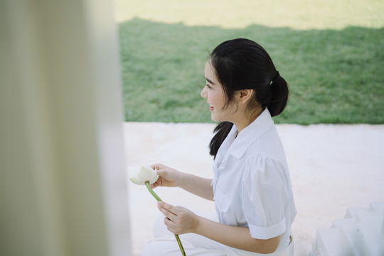 黑马尾姑娘坐在寺院的地板上，折好莲花瓣，准备送给和尚。