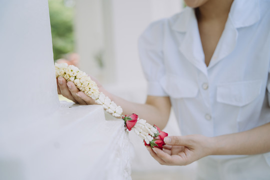 女人把茉莉花环掉在庙宇地板上时的剪短图像。