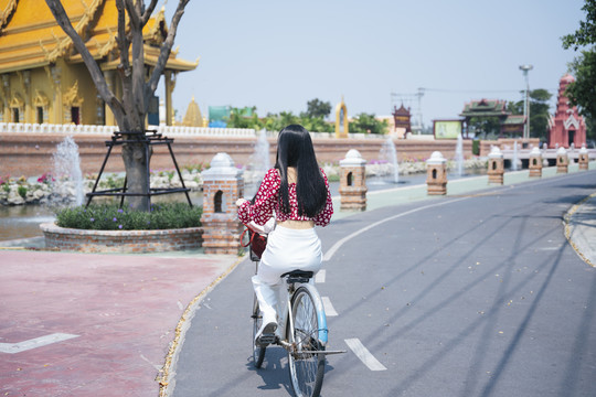 穿红衬衫的黑长发女孩骑自行车去传统旅游