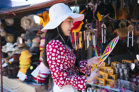 穿红衬衫、戴红帽子的黑色长发女孩喜欢漫步在当地的集市上，看看精彩的商品和产品。