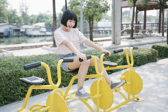 可爱的亚洲年轻女子鲍勃发型玩自行车在公园锻炼。