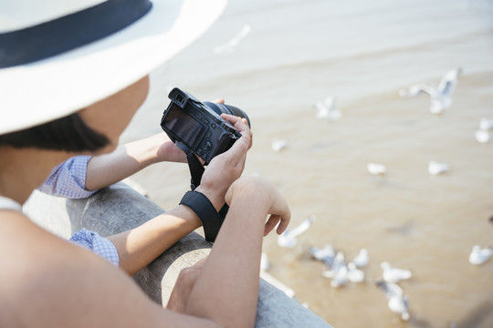 快乐的亚泰夫妇在海边用相机互相展示照片。在海上大桥上旅行。