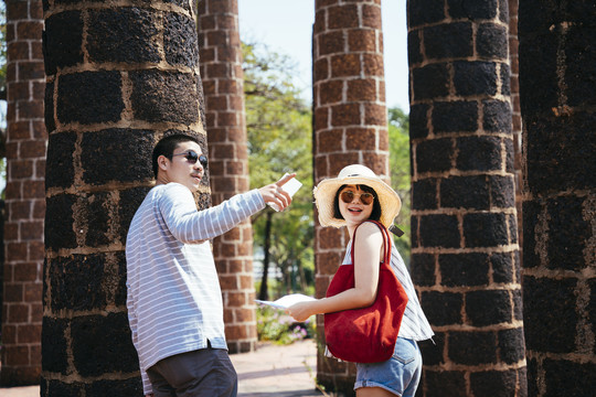 一对戴墨镜的亚洲游客夫妇在泰国古城遗址旅游。抢掠。