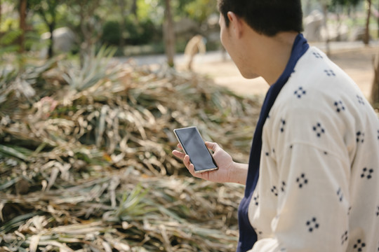 生态旅游-亚泰光头男子手持智能手机谈论当地商业。农业企业。