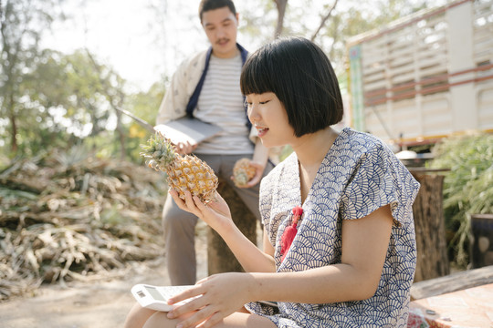 生态旅游-一对年轻的商人试图在网站上出售新鲜菠萝。水果网购业务。现代农民。