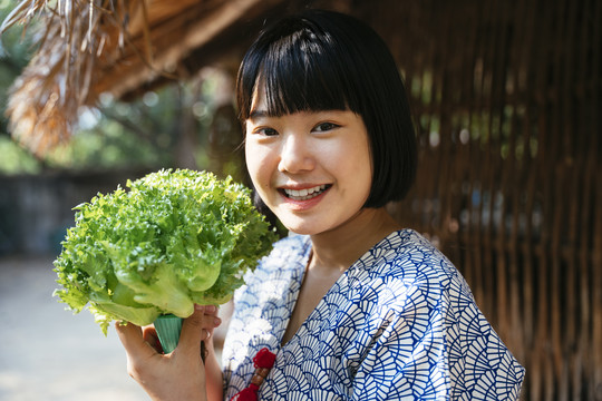 生态旅游——当地年轻农民手持绿色新鲜蔬菜从事农业经营。鲍勃发型女孩。素食主义者。