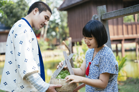 生态旅游-当地农民夫妇互相帮助从农场收获蔬菜放在篮子里。