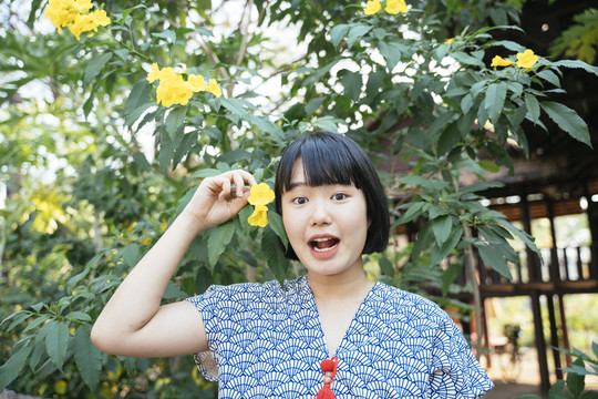 生态旅游-美丽的亚泰女子鲍勃手持黄花发型。特写镜头。