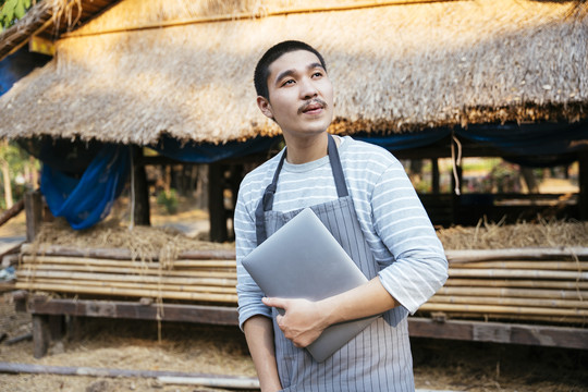 生态旅游——光头当地农民手持笔记本电脑的画像。农民用科技做生意。