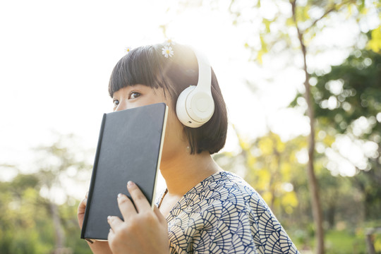 亚洲女人鲍勃发型听音乐用白色耳机在户外的自然公园。