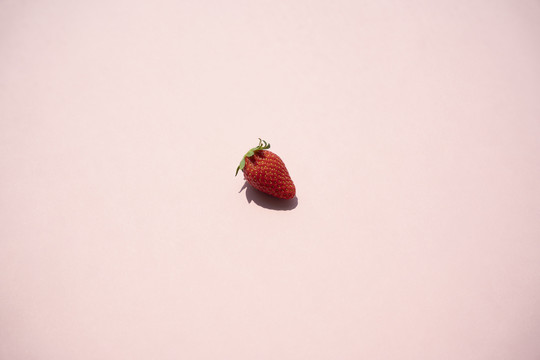 粉红色背景上有浅色和阴影的小草莓。