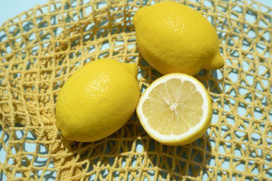 柠檬和切片柠檬黄网袋上的蓝色背景。
