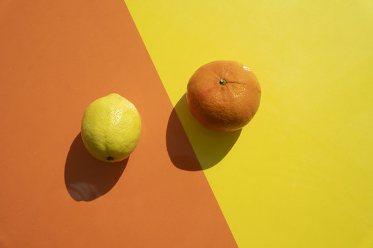 在黄色和橙色的背景上放柠檬、橘子和酸橙片。