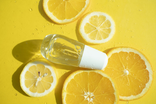 黄色背景上的柠檬片和一小瓶有光影的糖浆。