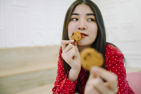 美丽的亚泰黑发红衫女子，双手捧着巧克力饼干。